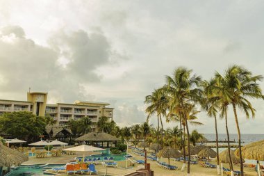 Otel manzarası çok güzel. Açık havuz, mavi güneş yatakları ve yeşil palmiye ağaçlarının arka planında şemsiyeler. Willemstad. Curacao. 09.18.2019.