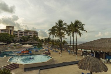 Otel manzarası çok güzel. Açık havuz, mavi güneş yatakları ve yeşil palmiye ağaçlarının arka planında şemsiyeler. Willemstad. Curacao. 09.18.2019.