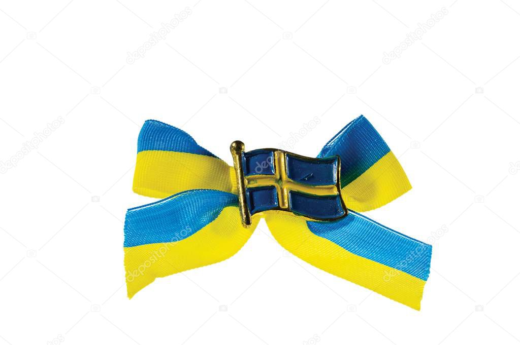 Close up macro view of metal badge in form of swedish flag on blue yellow bow.