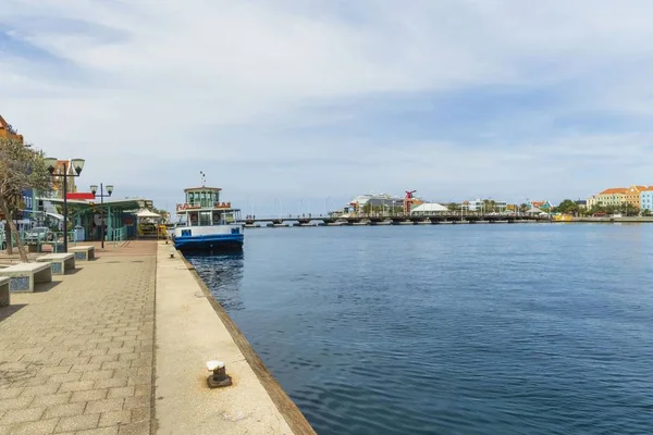 Beautiful view of coast line of Willemstad. Dark blue water surface of Atlantic ocean. Coast line with buildings merging with blue sky and white clouds. Willemstad. Curacao.