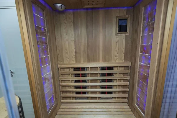 Kızıl ötesi sauna iç görünüş. Ahşap duvarlar, bank, seramik ısıtıcılar. Sağlıklı yaşam tarzı kavramı.