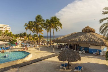 Otel manzarası çok güzel. Açık havuz, mavi güneş yatakları ve yeşil palmiye ağaçlarının arka planında şemsiyeler. Willemstad. Curacao. 09.20.2019.