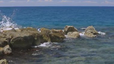 Taşların üzerinde fren yapan dalgaların muhteşem manzarası. Atlantik Okyanusu 'nun turkuaz suyu ve mavi arka planda büyük kayalar. Willemstad. Curacao
