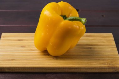 Ahşap zemin üzerinde su damlaları olan sarı biber manzarasını kapat. Güzel doğa geçmişi.