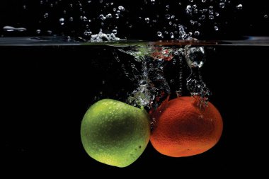 Siyah arka planda suya düşen renkli meyvelerin yakın görüntüsü. Muhteşem arka planlar..