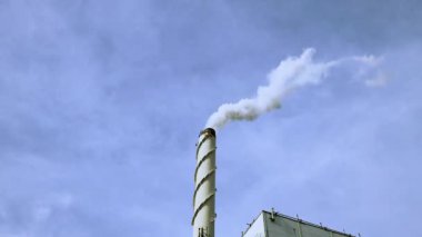 Mavi arka plandaki bacadan beyaz duman görüntüsü. Ekoloji ve sera etkisi kavramı.