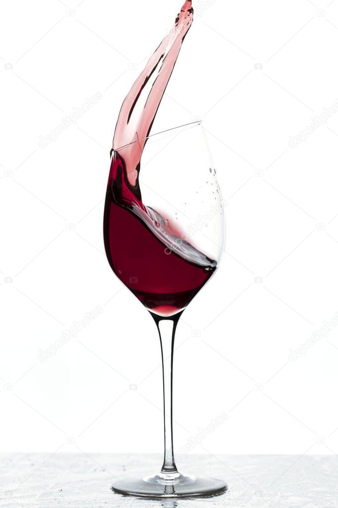 Close up view of splashing red wine in glass isolated on white background. 