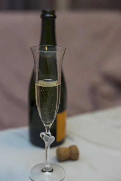 Close up view of champagne glass on open bottle background. Drinks concept.