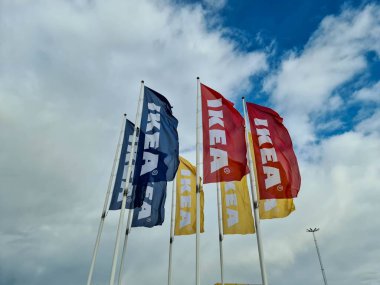 Büyük beyaz bulutlarla kaplı mavi gökyüzünde büyük renkli IKEA bayraklarının güzel manzarası. Avrupa. İsveç. Uppsala. 04.17.2020.