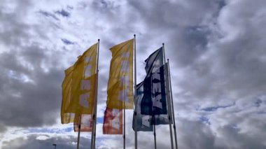 Büyük beyaz bulutlarla kaplı mavi gökyüzünde büyük renkli IKEA bayraklarının güzel manzarası. Avrupa. İsveç. Uppsala. 04.17.2020.