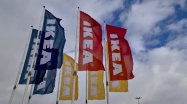 Büyük beyaz bulutlarla kaplı mavi gökyüzünde büyük renkli IKEA bayraklarının güzel manzarası. Avrupa. İsveç. Uppsala. 04.17.2020.