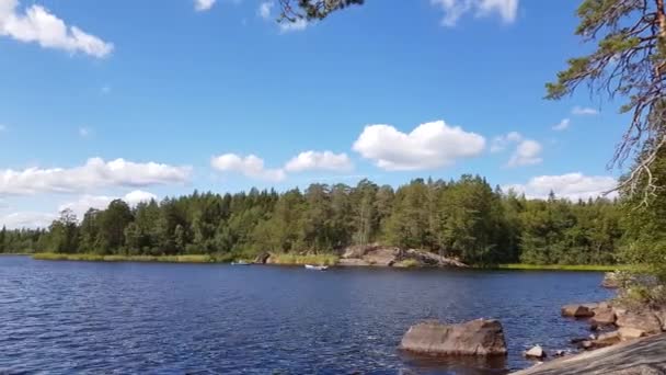 美丽的自然景观 湖上有岩石海岸 蓝水表面 蓝天绿树 白云背景 — 图库视频影像