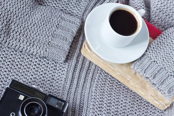 Hög vinkel skott av en vit keramisk kopp med vit kaffe, bok och en gammal kamera av en pullover . — Stockfoto