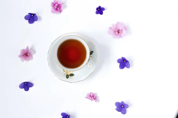 Xícara de chá e ramo de pequena flor rosa e lilás no fundo branco — Fotografia de Stock