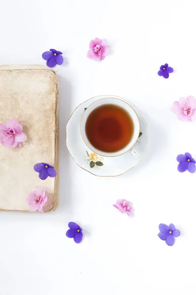 Oude retro boek en kopje thee op witte tafel . — Stockfoto