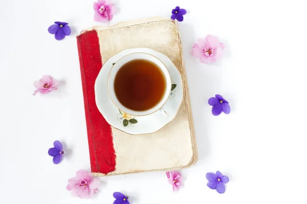 Livro antigo com chá ou café com flores em fundo branco  . — Fotografia de Stock