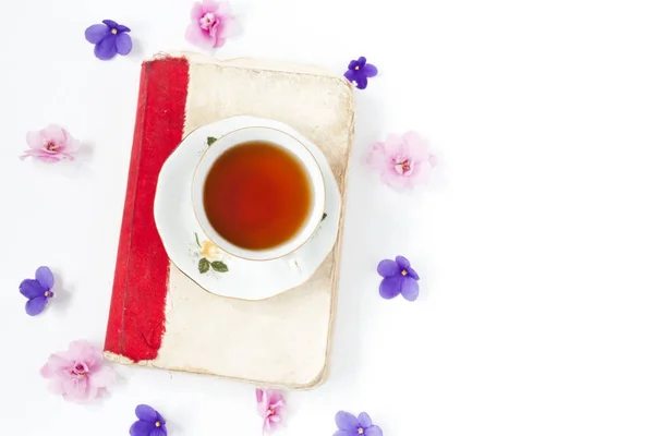 Livro antigo com chá ou café com flores em fundo branco  . — Fotografia de Stock