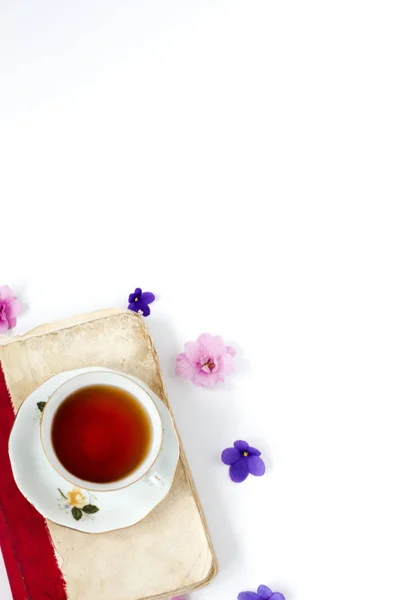 Fond romantique avec tasse de thé, fleurs de lilas et livre rétro sur table blanche  . — Photo