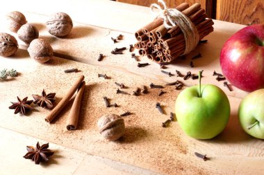 Taze kırmızı ve yeşil elma, tarçın, anason yıldız, ceviz ahşap arka plan üzerinde