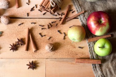 Taze kırmızı ve yeşil elma, tarçın, anason yıldız, ceviz ve fındık eski bir ahşap zemin üzerine