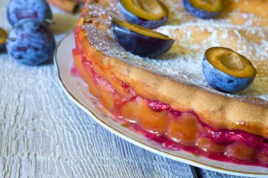 Beyaz ahşap zemin üzerinde rustik erikli kek.