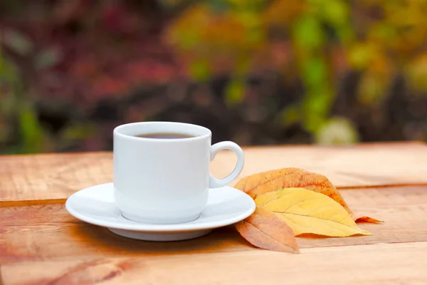 Feuilles d'automne et tasse de café chaud et fumant. Table en bois sur fond de feuilles dorées. Saison d'automne, temps libre et concept de pause café .. — Photo