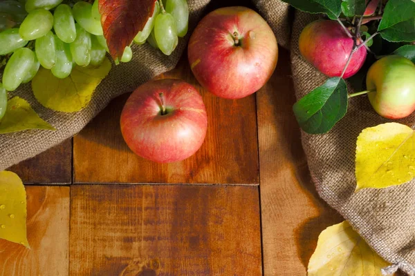 Färsk skörd av äpplen. Natur tema med gröna druvor och äpple på trä bakgrund. Naturen frukt koncept.. — Stockfoto