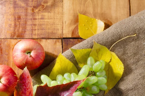 Äpplen på träbord med hösten på trä bakgrund — Stockfoto