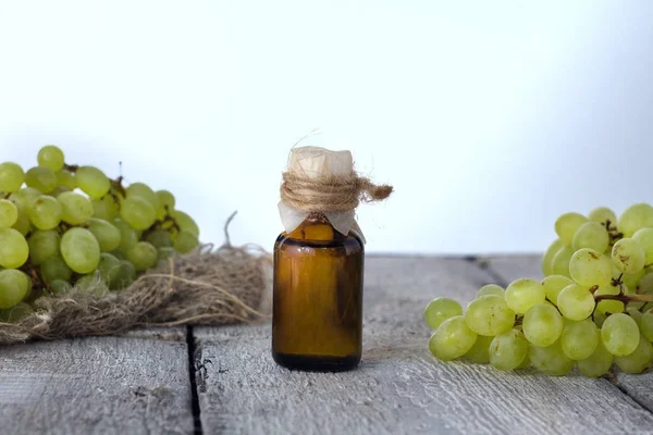 Bottle with grape seed essential oil on a wooden table