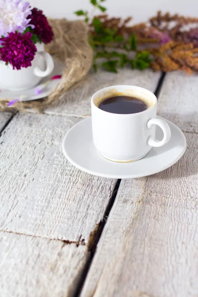 Romantiska bakgrund med kopp kaffe, blommor över vitt bord. — Stockfoto