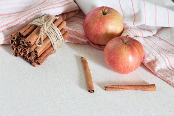 Färska mogna röda äpplen och kanelstänger på vit trä bakgrund. — Stockfoto