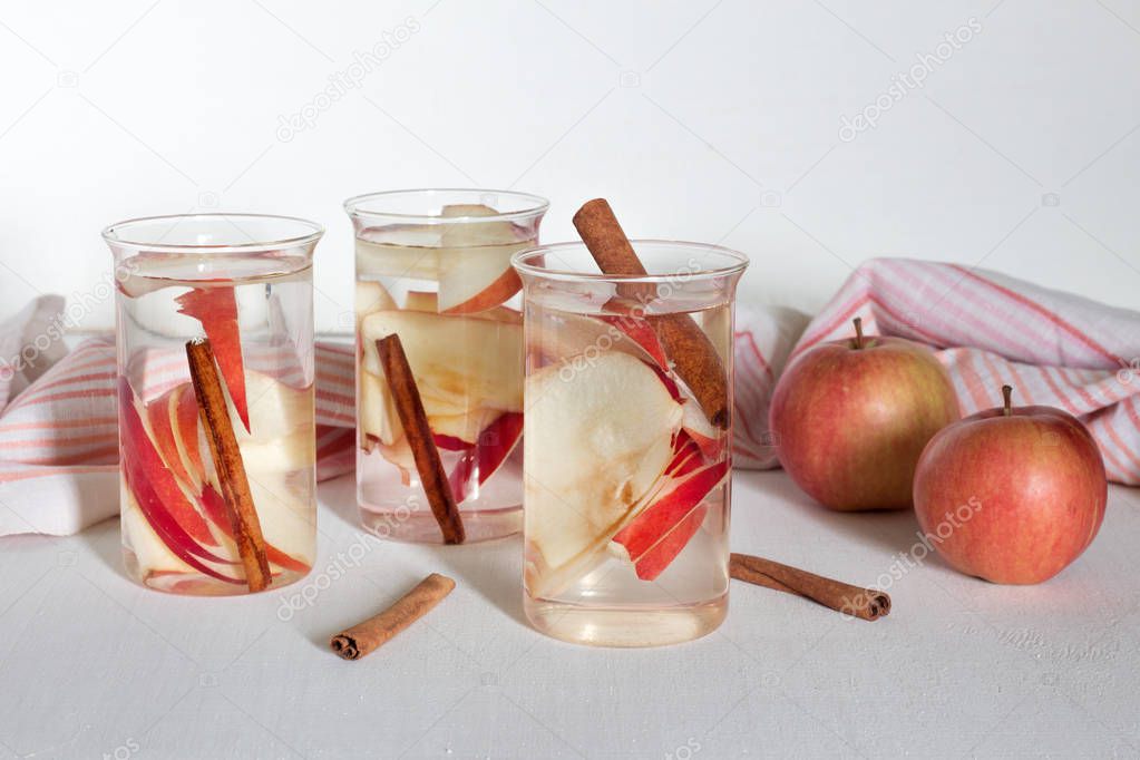 Infused water with apple and cinnamon on white wooden background