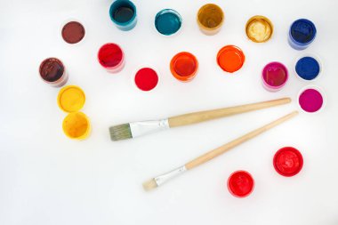 Sanatsal renkli boya ve fırça, birbirine yakın sergilenen. Üstten Görünüm. Beyaz bir arka plan üzerinde