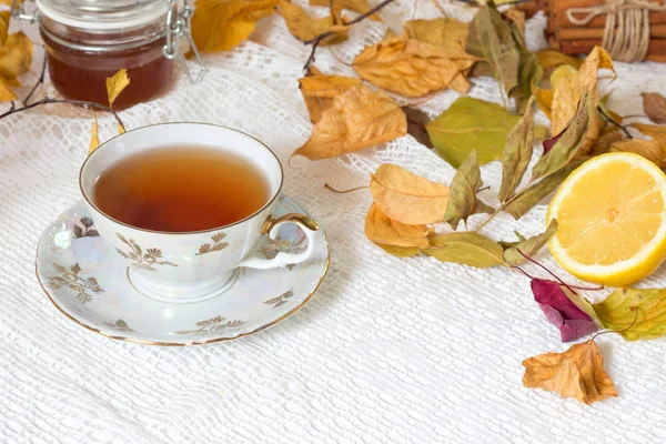 Secangkir teh dengan daun musim gugur dan serbet putih dengan latar belakang putih . — Stok Foto