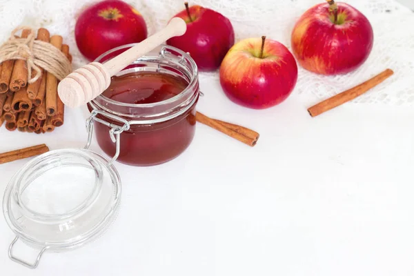 Miele in vaso di vetro e mela con bastoncini di cannella su fondo bianco — Foto Stock