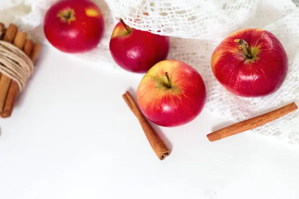 Färska mogna röda äpplen och kanelstänger på vit trä bakgrund — Stockfoto