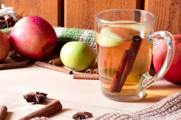 Mele rosse su una tavola di legno, tazza di vetro di erbe o tè e cannella . — Foto Stock