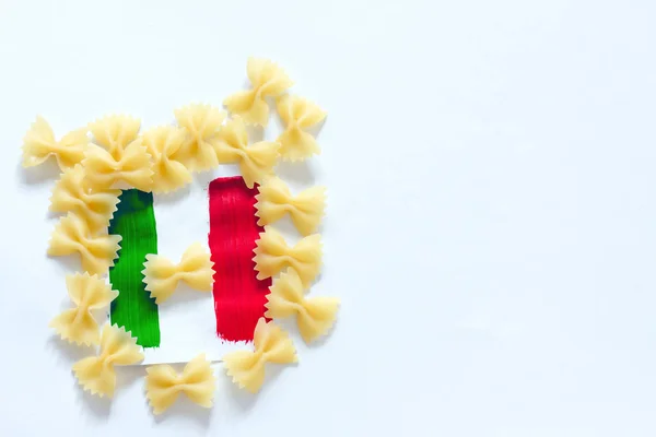 Pasta cruda y bandera de Italia sobre fondo blanco —  Fotos de Stock