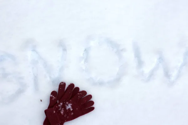 Guantes de invierno en la nieve con inscripción de nieve. Textura brillante de laico plano . . —  Fotos de Stock