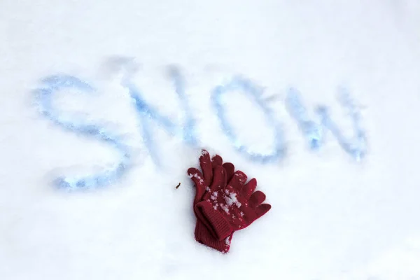 Guantes de invierno yacen en la nieve con la inscripción nieve  . —  Fotos de Stock