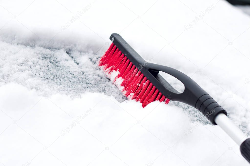 Transportation, winter, weather, people and vehicle concept - man cleaning snow from car with brush .