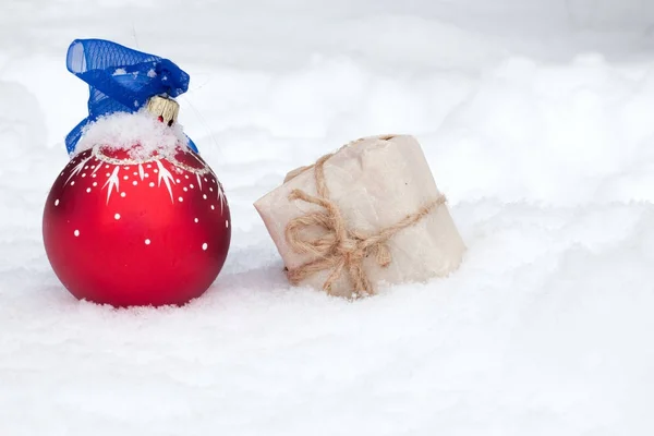 Bola de Navidad y regalo en la nieve —  Fotos de Stock