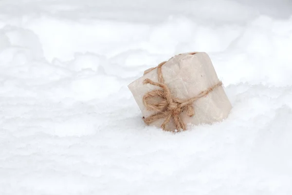 Caixa de presente branca na neve fresca contra um fundo — Fotografia de Stock