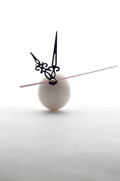 白い背景の上の卵と時計の針 ストック画像