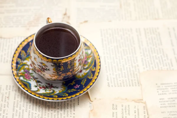 Tasse vintage de café aromatique fort sur le fond de feuilles imprimées de l'ancien livre — Photo