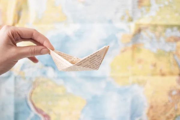 Bateau en papier fait de vieux papier imprimé sur fond de carte du monde. Voyage concept de mer — Photo