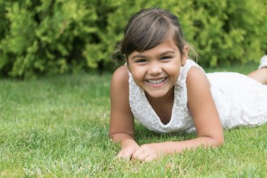 Gülen esmer kız çim üzerinde yalan