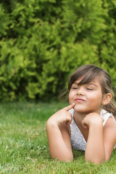 Mutlu küçük kız bir çim üzerinde yalan. 