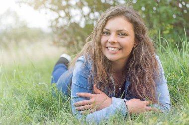 Gülümseyen genç kız çim yalan söylüyor