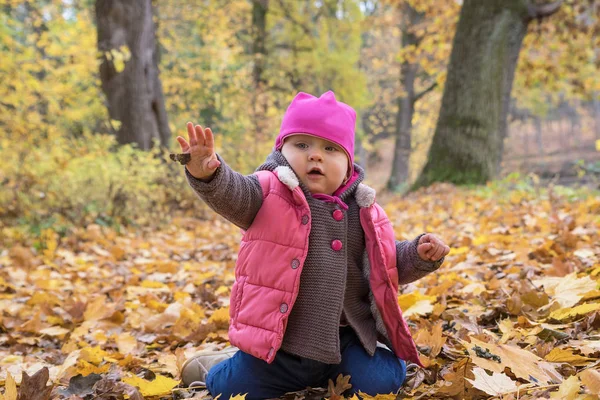 Niedliches kleines Mädchen wirft die Blätter des Baumes — Stockfoto